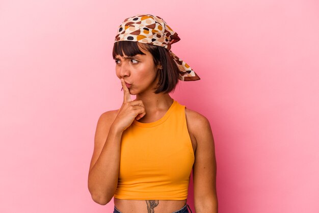 Young mixed race woman isolated on pink background keeping a secret or asking for silence