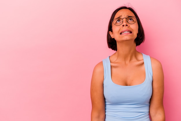 Young mixed race woman isolated on pink background shouting very angry, rage concept, frustrated.