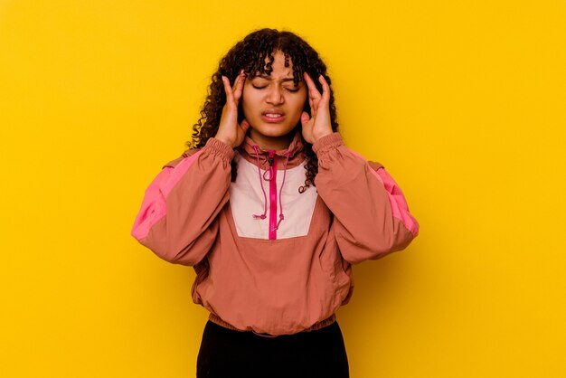 Young mixed race woman isolated on pink background touching temples and having headache