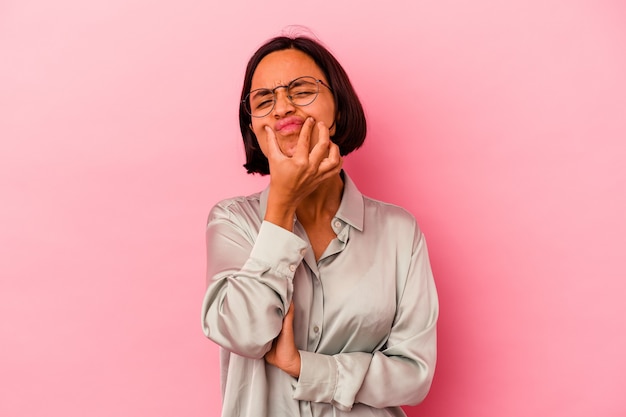 Young mixed race woman isolated on pink doubting between two options.