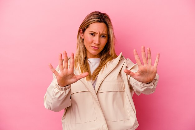 Young mixed race woman isolated on pink rejecting someone showing a gesture of disgust.