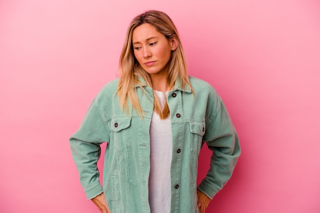 Young mixed race woman isolated on pink wall confused, feels doubtful and unsure.