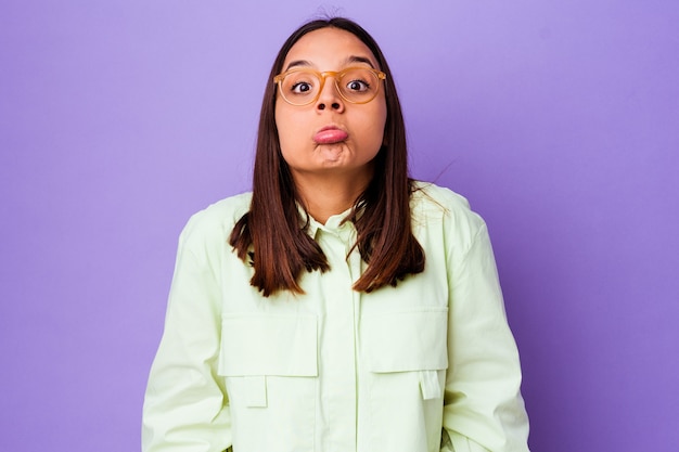 Young mixed race woman isolated shrugs shoulders and open eyes confused.