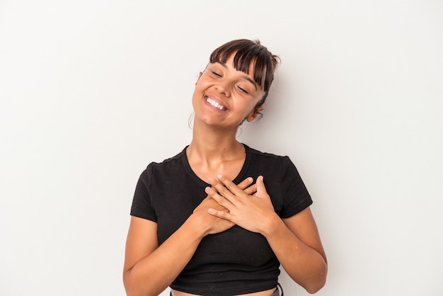 Young mixed race woman isolated on white background  has friendly expression, pressing palm to chest. Love concept.