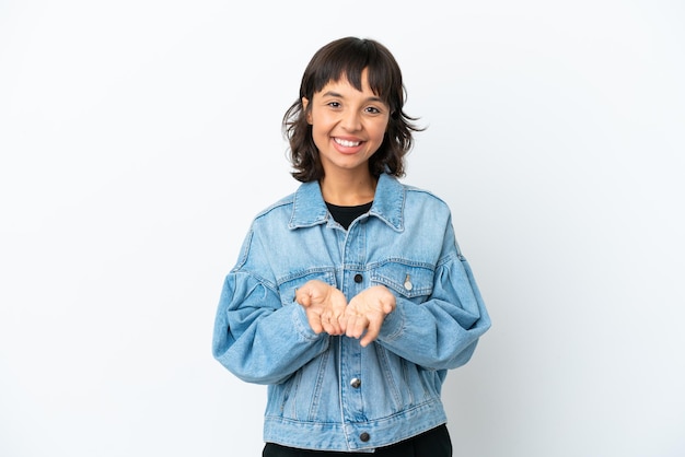 Young mixed race woman isolated on white background holding copyspace imaginary on the palm to insert an ad