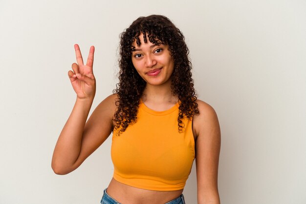 Young mixed race woman isolated on white background joyful and carefree showing a peace symbol with fingers.