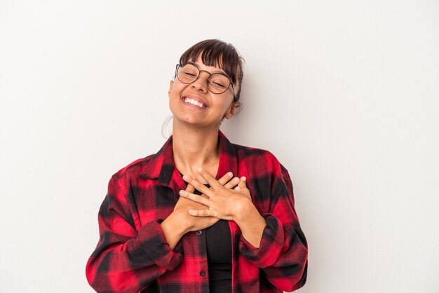 Young mixed race woman isolated on white background laughing keeping hands on heart, concept of happiness