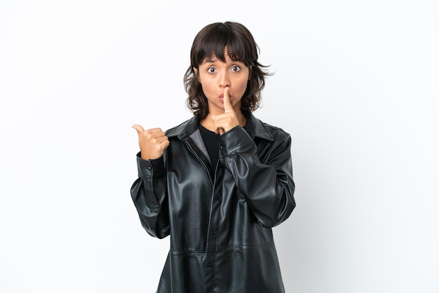 Young mixed race woman isolated on white background pointing to the side and doing silence gesture