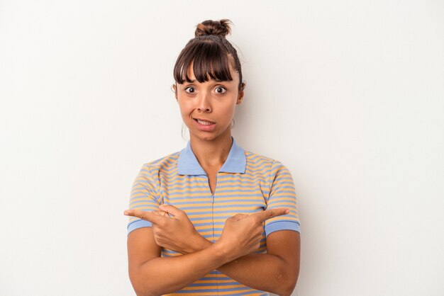 Young mixed race woman isolated on white background  points sideways, is trying to choose between two options.