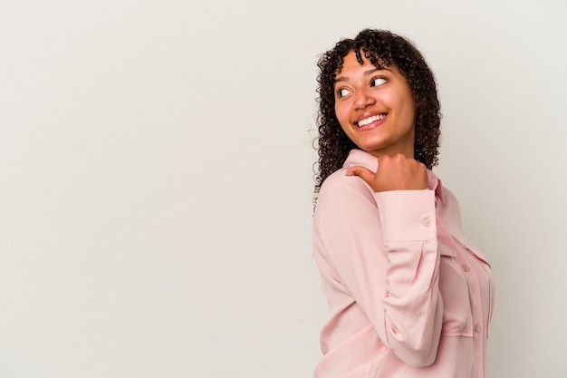 Young mixed race woman isolated on white background points with thumb finger away, laughing and carefree.