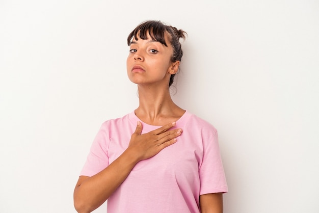 Young mixed race woman isolated on white background  taking an oath, putting hand on chest.