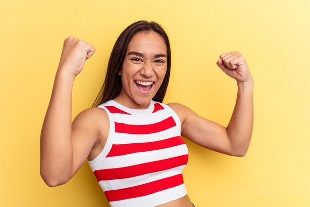 Young mixed race woman isolated on yellow background cheering carefree and excited. Victory concept.