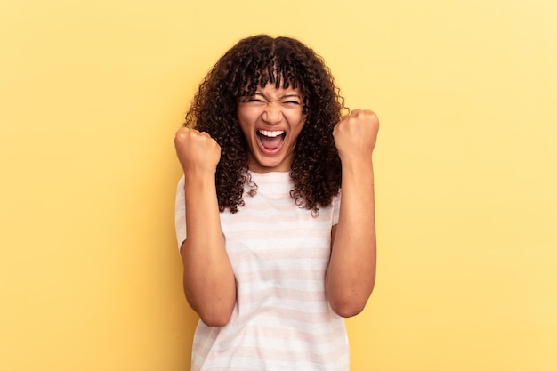 Photo young mixed race woman isolated on yellow background cheering carefree and excited victory concept