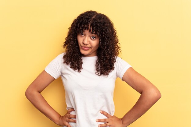 Young mixed race woman isolated on yellow background confused, feels doubtful and unsure.