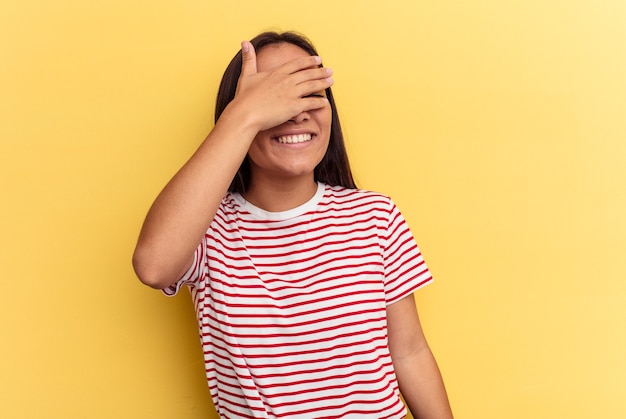 Young mixed race woman isolated on yellow background covers eyes with hands, smiles broadly waiting for a surprise.