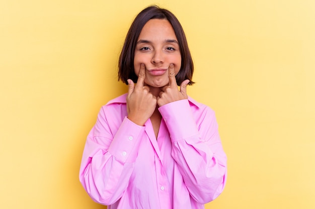 Young mixed race woman isolated on yellow background doubting between two options.