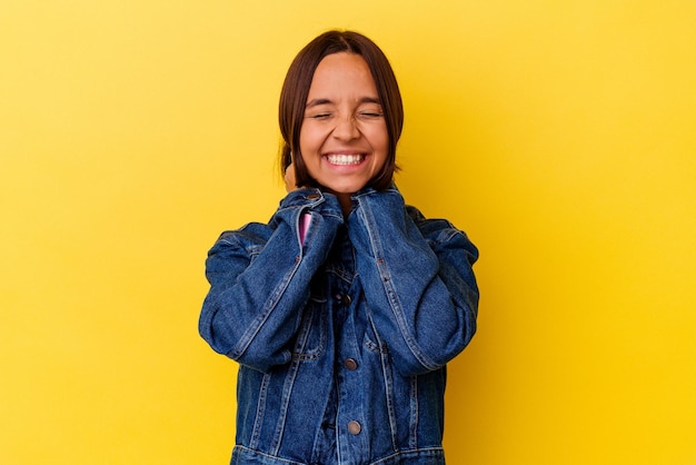 Photo young mixed race woman isolated on yellow background feeling confident, with hands behind the head.