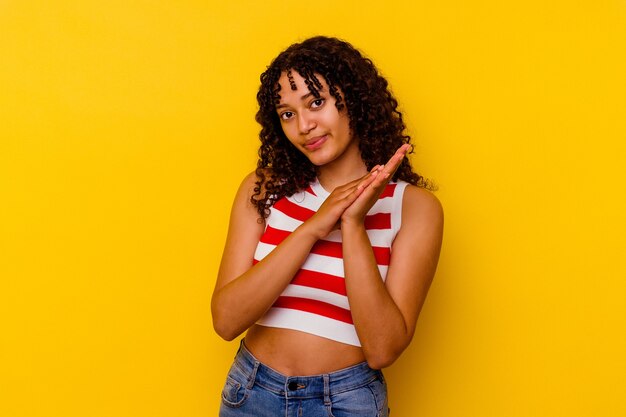 Young mixed race woman isolated on yellow background feeling energetic and comfortable, rubbing hands confident
