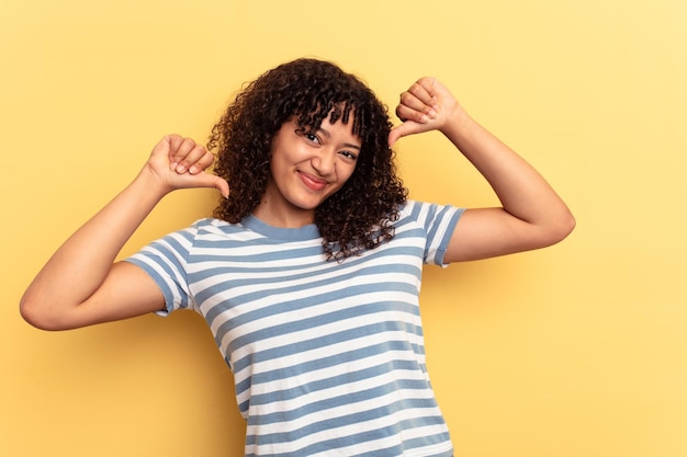 Young mixed race woman isolated on yellow background feels proud and self confident example to follow