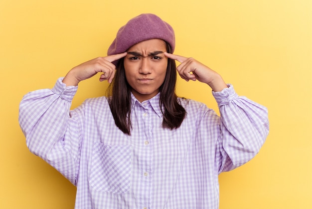 Young mixed race woman isolated on yellow background focused on a task, keeping forefingers pointing head.