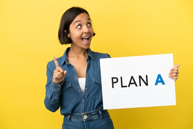 Photo young mixed race woman isolated on yellow background holding a placard with the message plan a and thinking