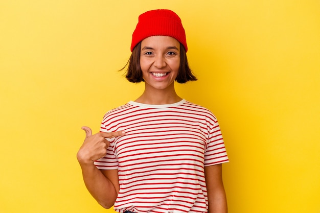 Photo young mixed race woman isolated on yellow background person pointing by hand to a shirt copy space, proud and confident