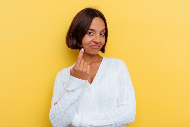 Young mixed race woman isolated on yellow background pointing with finger at you as if inviting come closer.