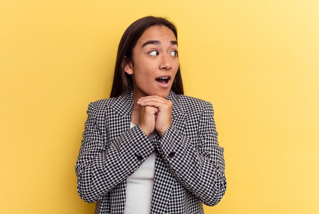 Young mixed race woman isolated on yellow background praying for luck, amazed and opening mouth looking to front.