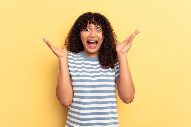 Young mixed race woman isolated on yellow background screaming to the sky looking up frustrated