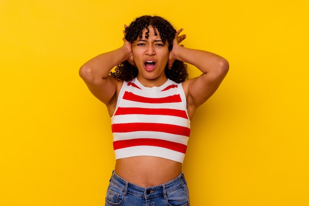 Young mixed race woman isolated on yellow background screaming with rage.