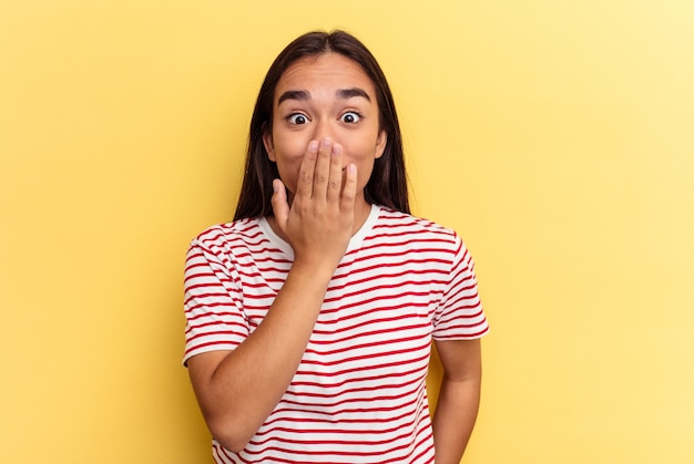 Young mixed race woman isolated on yellow background shocked, covering mouth with hands, anxious to discover something new.