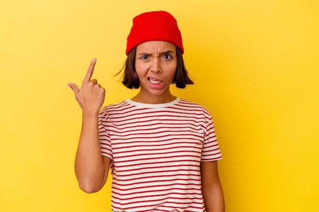 Young mixed race woman isolated on yellow background showing a disappointment gesture with forefinger.