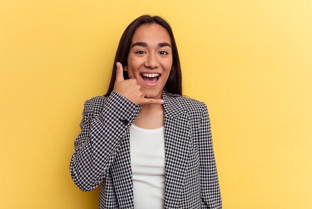 Young mixed race woman isolated on yellow background showing a mobile phone call gesture with fingers.