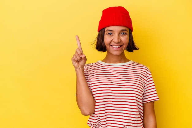 Young mixed race woman isolated on yellow background showing number one with finger.