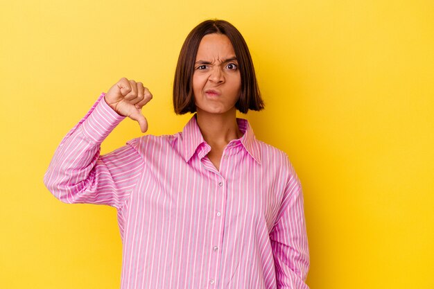 Young mixed race woman isolated on yellow background showing thumb down, disappointment concept.