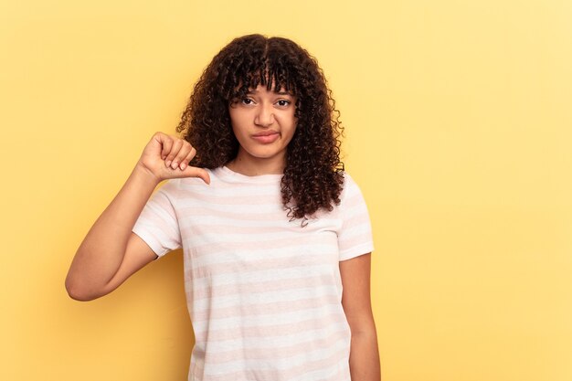 Young mixed race woman isolated on yellow background showing thumb down, disappointment concept.