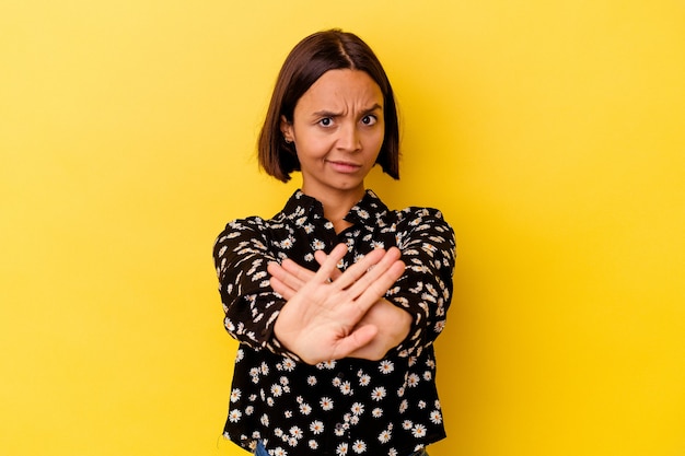 Young mixed race woman isolated on yellow background standing with outstretched hand showing stop sign, preventing you.