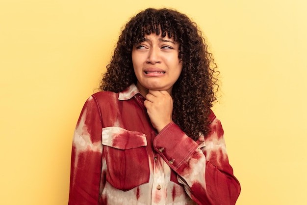 Foto giovane donna di razza mista isolata su sfondo giallo soffre di dolore alla gola a causa di un virus o di un'infezione