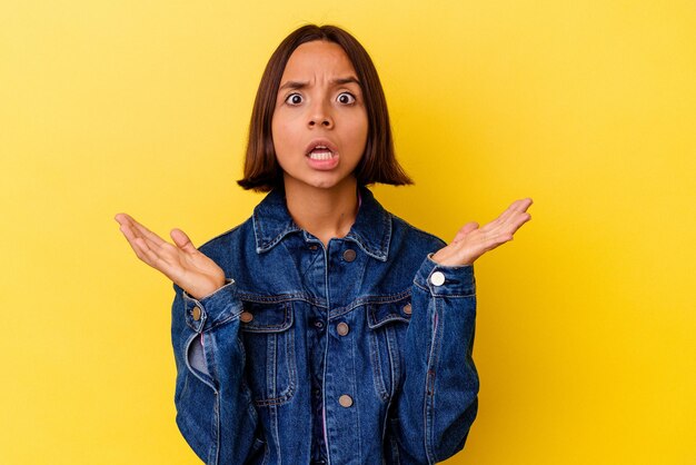 Young mixed race woman isolated on yellow background surprised and shocked.