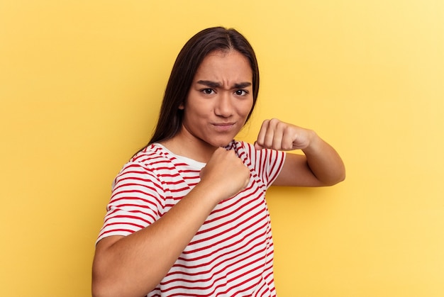 Young mixed race woman isolated on yellow background throwing a punch, anger, fighting due to an argument, boxing