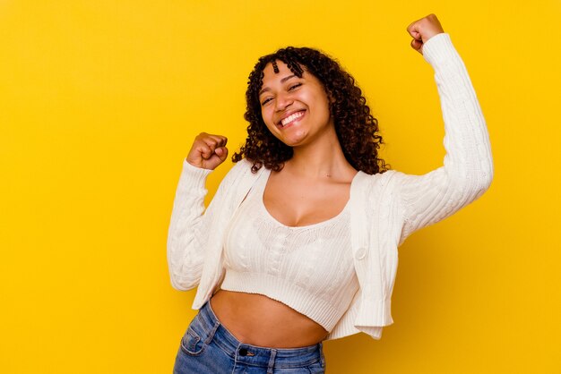 Young mixed race woman isolated on yellow dancing and having fun