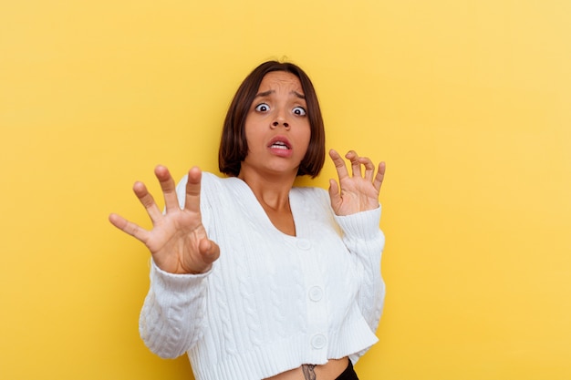 Young mixed race woman isolated on yellow wall being shocked due to an imminent danger