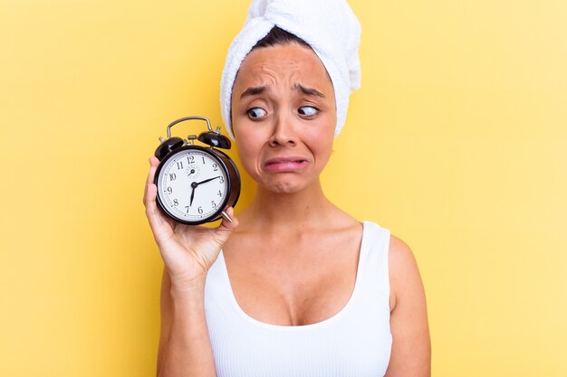 Young mixed race woman late for work isolated on yellow background