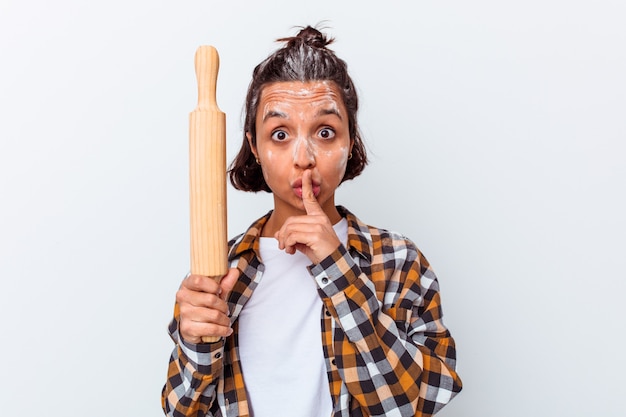 Young mixed race woman making bread isolated on white background keeping a secret or asking for silence.