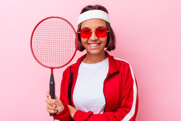 Young mixed race woman playing badminton isolated on pink wall