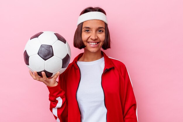 Young mixed race woman playing soccer isolated on pink wall happy, smiling and cheerful.