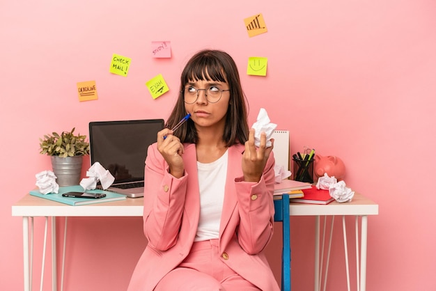 写真 ピンクの背景で隔離の紙を保持している部屋で試験を準備している若い混血の女性