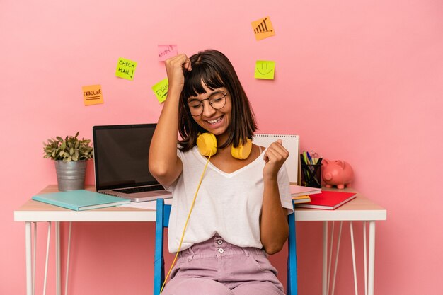 Young mixed race woman preparing a exam in the room listening to music isolated on pink background celebrating a special day, jumps and raise arms with energy.