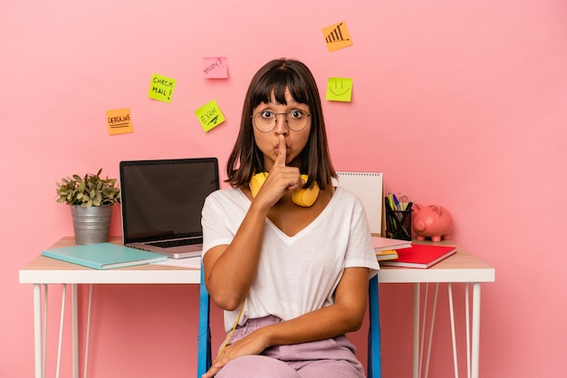 Young mixed race woman preparing a exam in the room listening to music isolated on pink background keeping a secret or asking for silence.