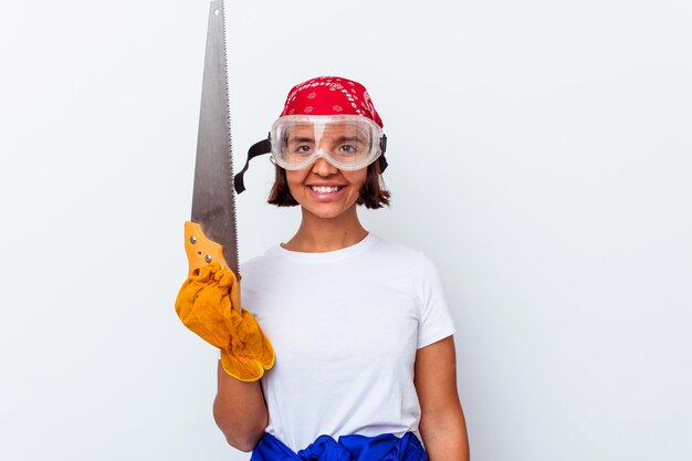 Young mixed race woman repairing her home with a saw isolated on white wall